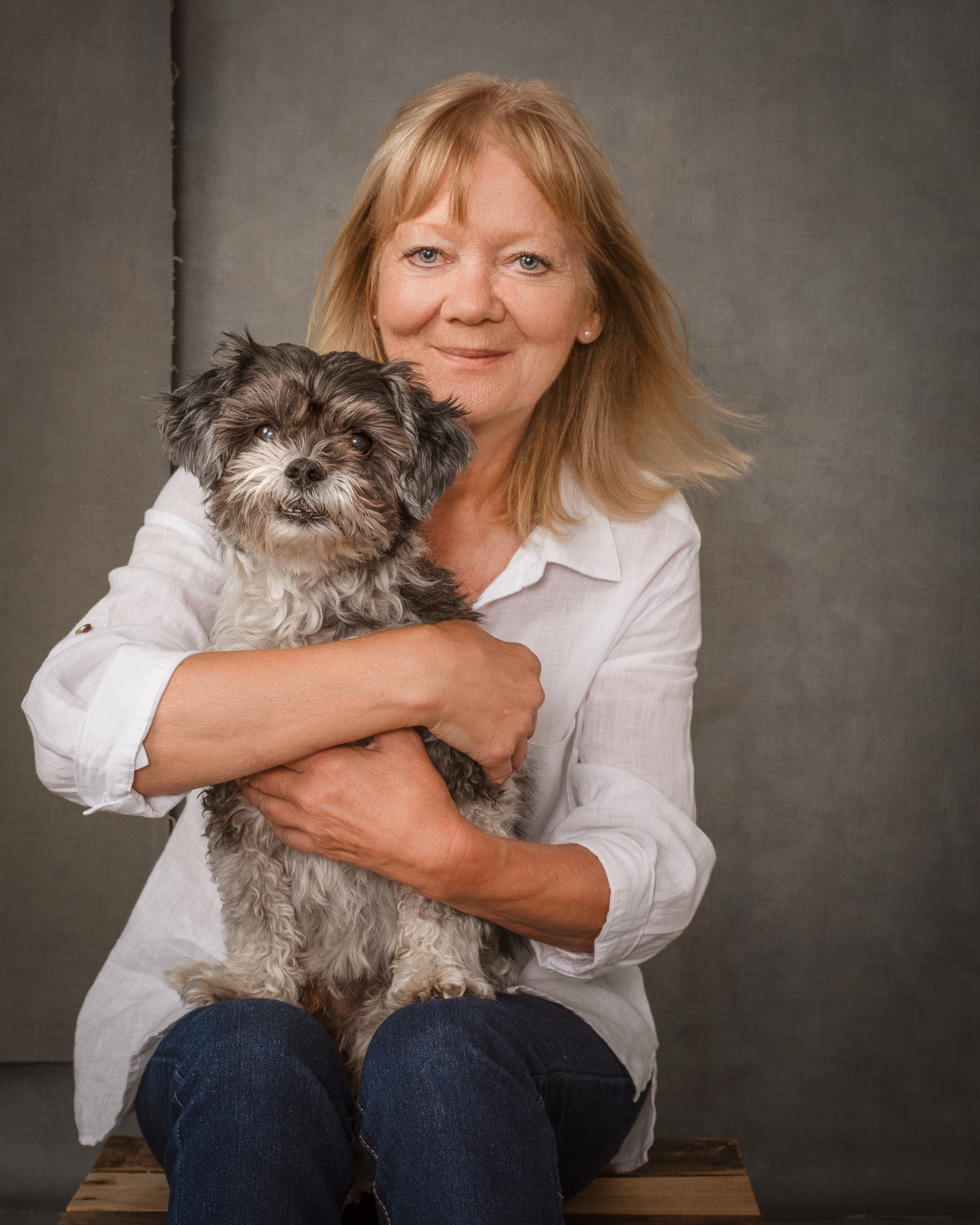 blonde-woman-sitting-on-a-box-with-a-small-black-and-white-dog